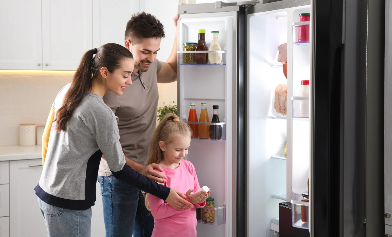 A family in a modern kitchen opening the fridge