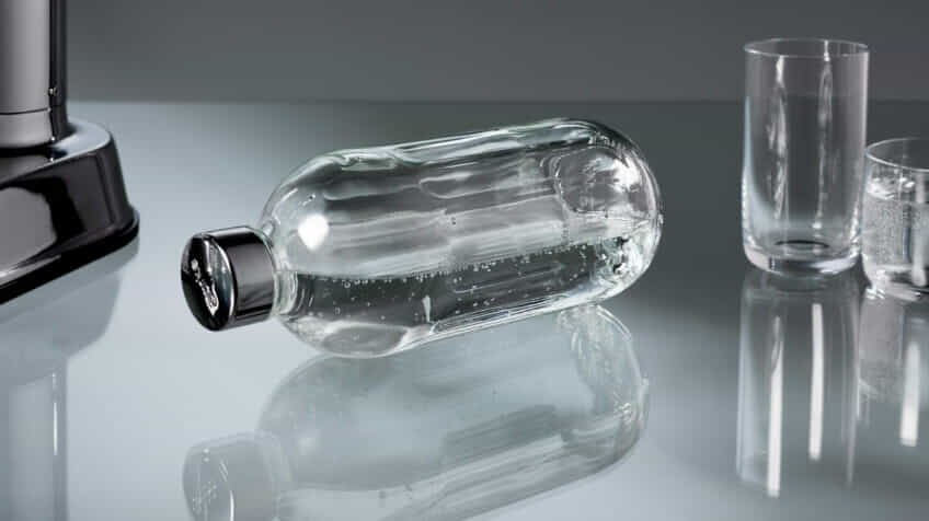 The aarke carbonator 3 and carbonator pro side by side on a modern kitchen bench surrounded by aarke bottles