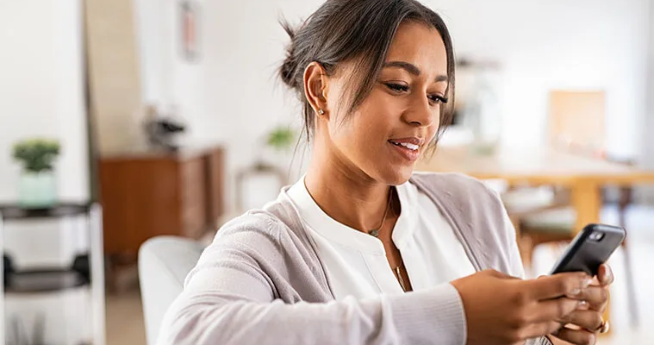 Woman uses her smartphone while relaxing on the couch at home