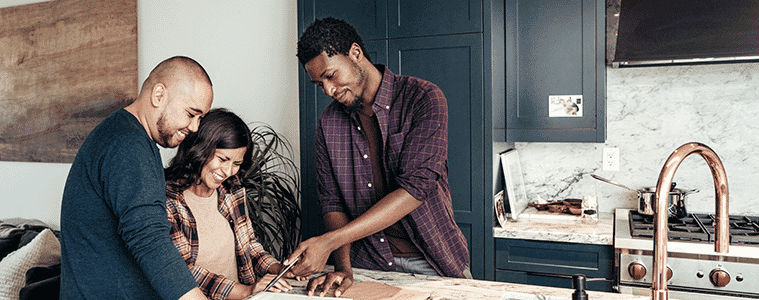 A husband and wife look at swatches with the help of a kitchen designer when planning a new kitchen