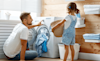 A father and daughter place a load of washing into a front loading washing machine in their laundry