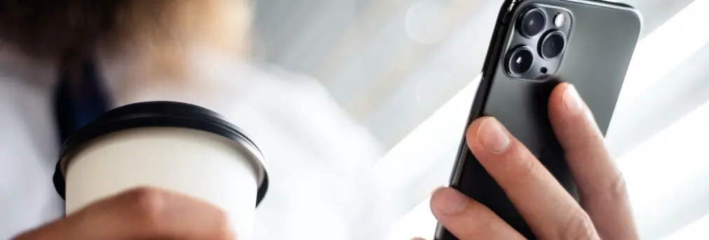 Person Holding a Phone and Coffee Cup
