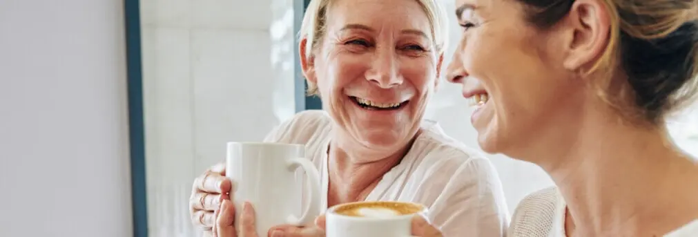 Two women laughing and enjoying a cup of coffee