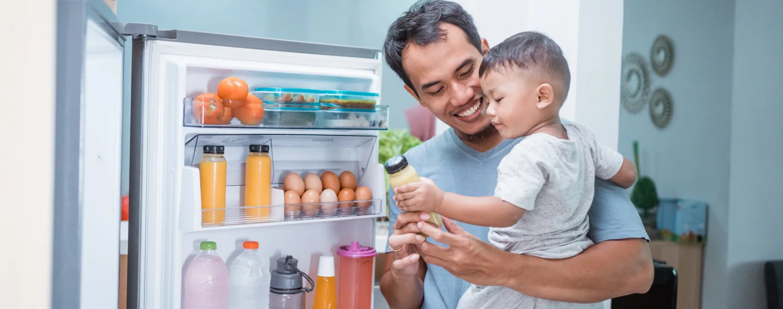 Image of a man and child grabbing a juice bottle from a fridge