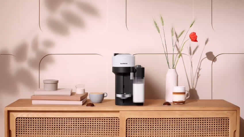 A new Nespresso Vertuo Lattissima Coffee Machine in black on a bunch making a coffee and frothing milk The Good Guys