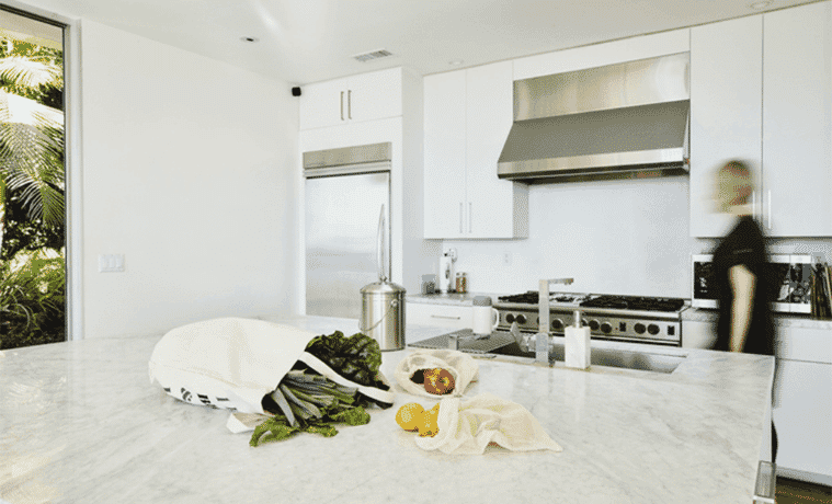A white kitchen with fresh produce on the island