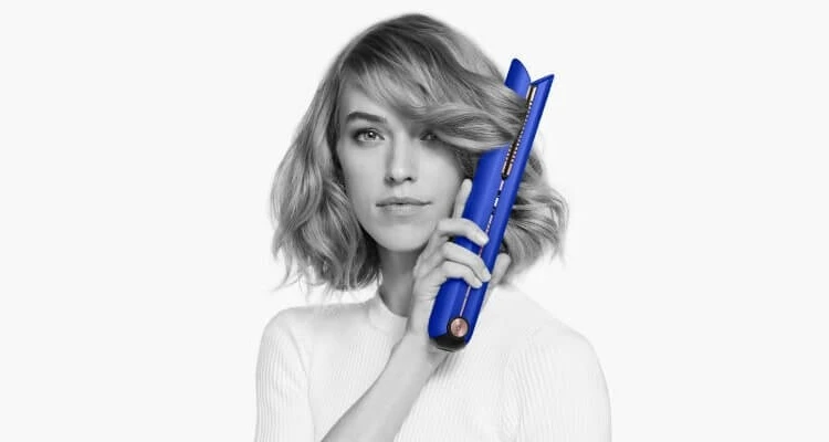 Woman using Dyson Blue Blush Hair straightener to giver her hair a wave.