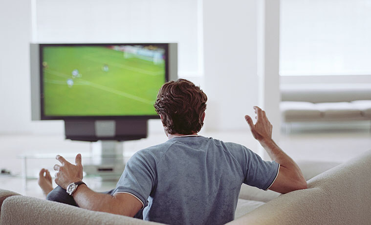 Man watching football on television rear view