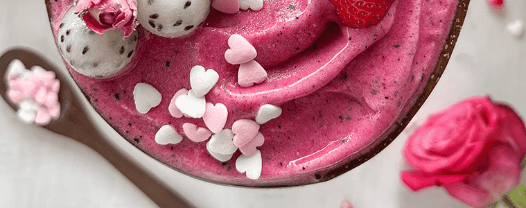 Blueberry icecream in a glass with lychee balls and heart shaped sprinkles on top