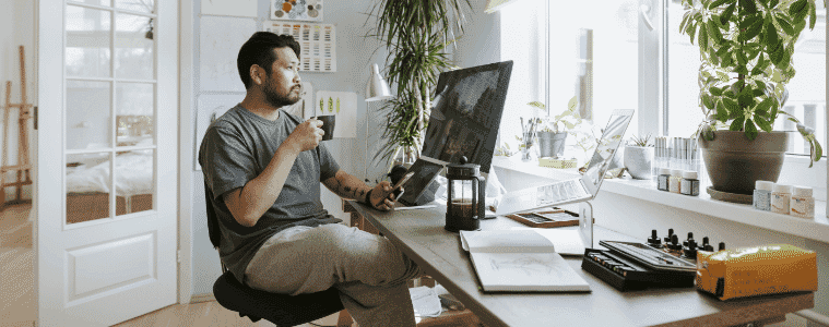 A man takes a contemplative moment during a coffee break in his home office