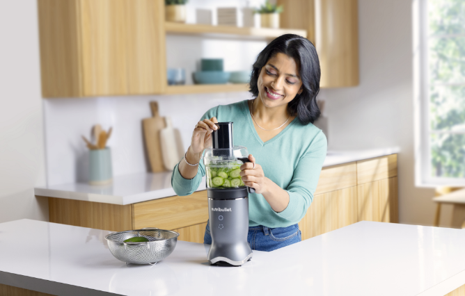 Woman using her Nutribullet blender as a food processor in her kitchen. 