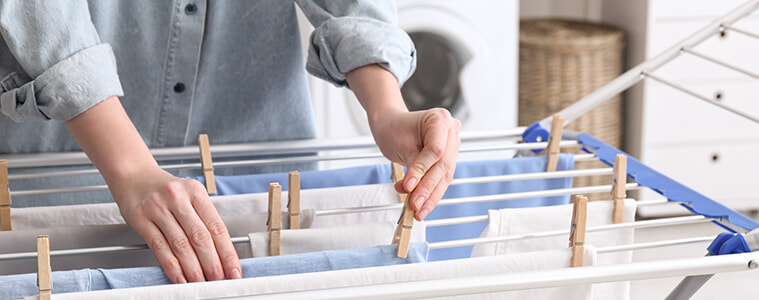a lady hanging up her wet laundry inside with pegs