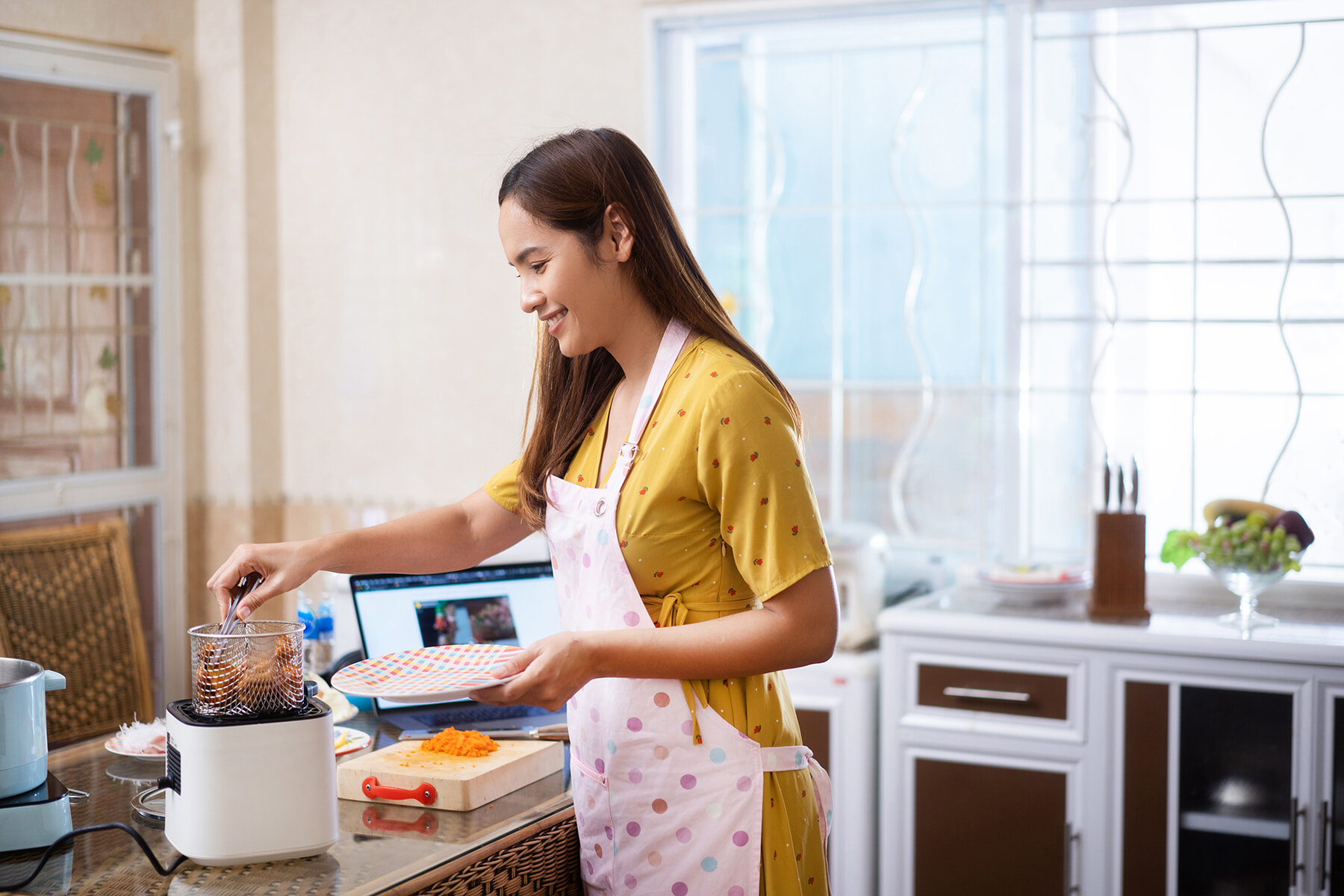 Happy woman using an air fryer in her kitchen