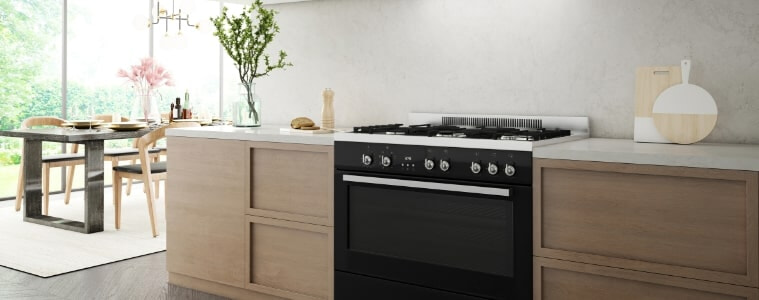 A black freestanding oven in a light timber and white kitchen