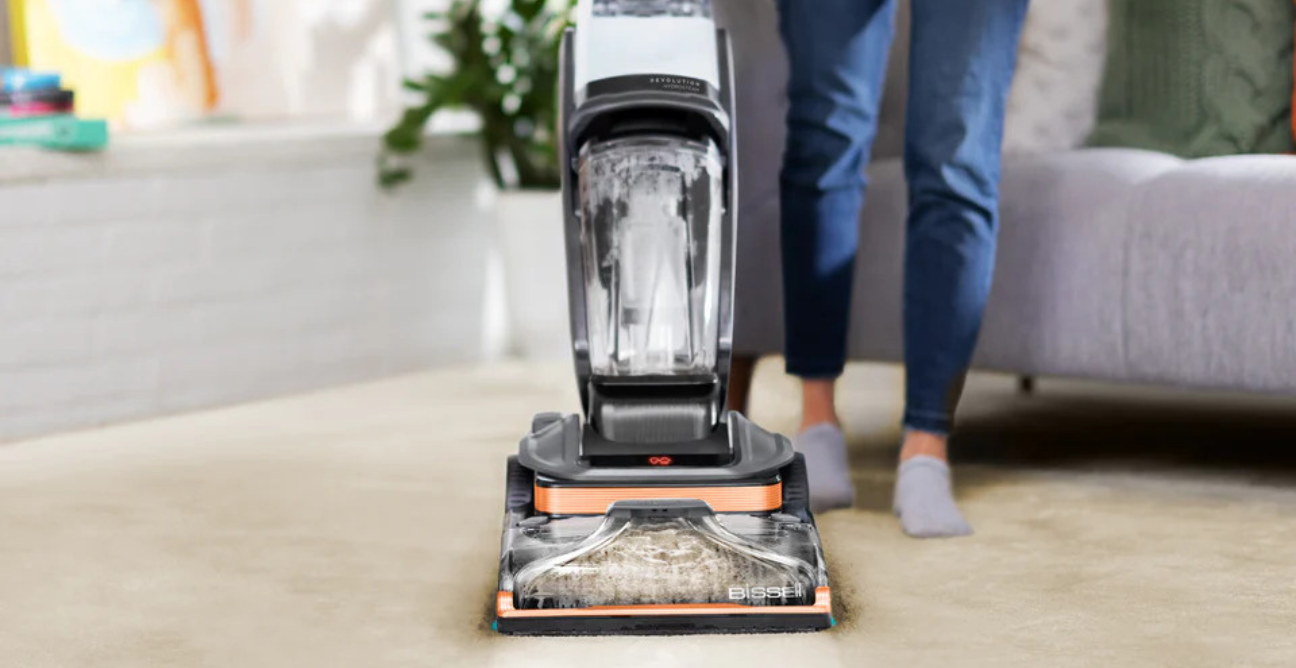 Bissell carpet cleaner being pushed across a cream carpet in a bright living room