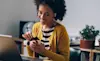 A woman opens up a small Christmas gift in front of her laptop