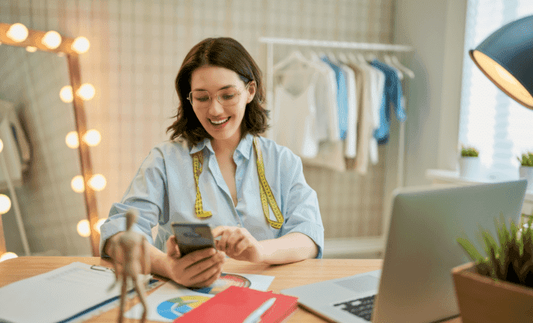 Woman happily working on her smartphone in her small business