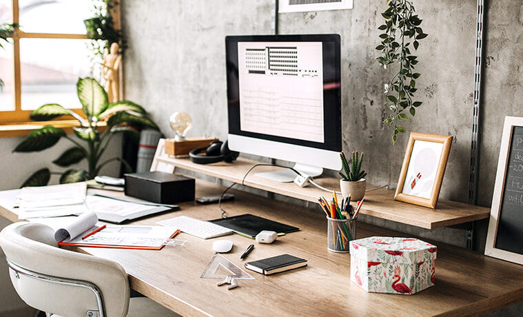 Modern home office with concretelook walls plants and a timber desk with a sleek PC and tablet