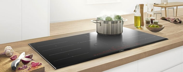 A builtin cooktop on a blonde timber butchers block countertop
