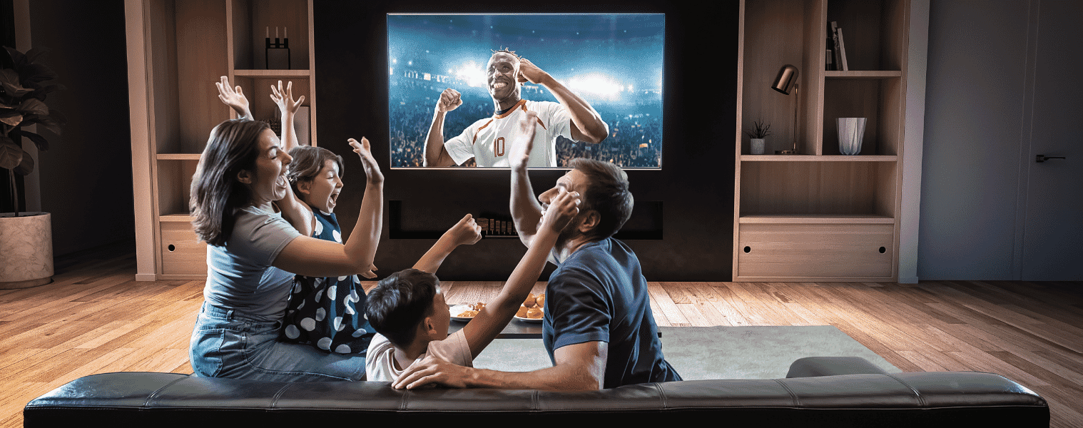 A family celebrating whilst watching sport on the TV in their living room