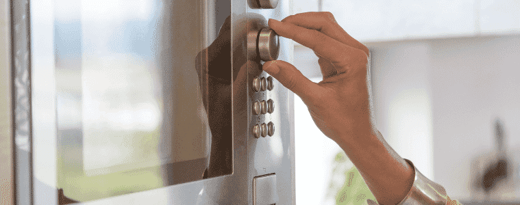 A person turns a dial on their microwave