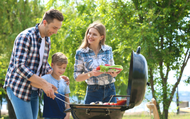 Father grilling at an outdoor barbecue with his family