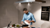 Male preparing dinner on a cooktop with a view of the ventilation boosting performance of the Beko rangehood.