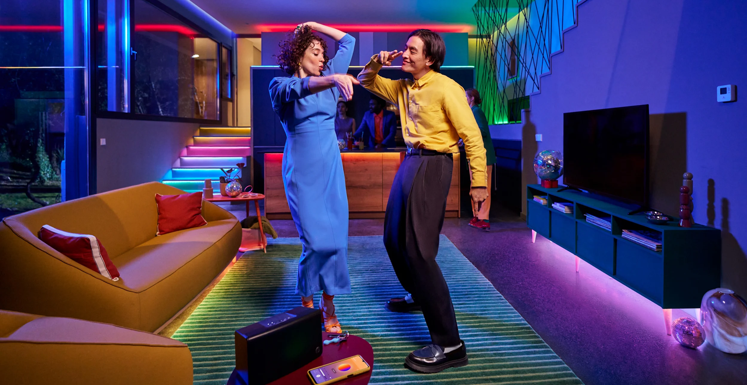 Image of a man and woman dancing in a living room lit up by WiZ lighting