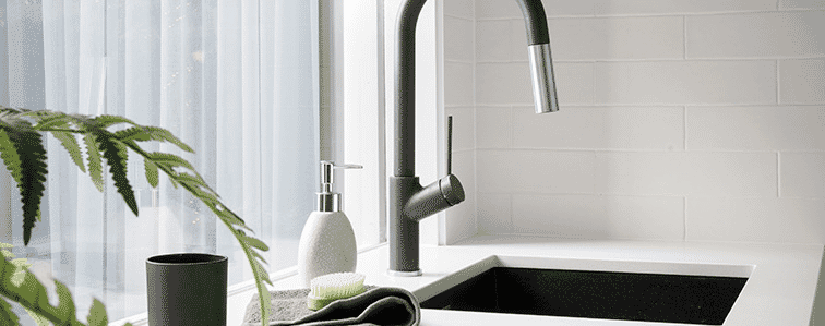 Detail of white benchtop with underbench laundry basin and gooseneckstyle black tap