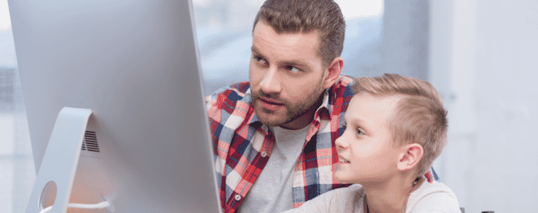 Father and son look at desktop at home 