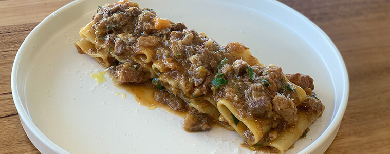 Single portion of pasta ragu on white plate