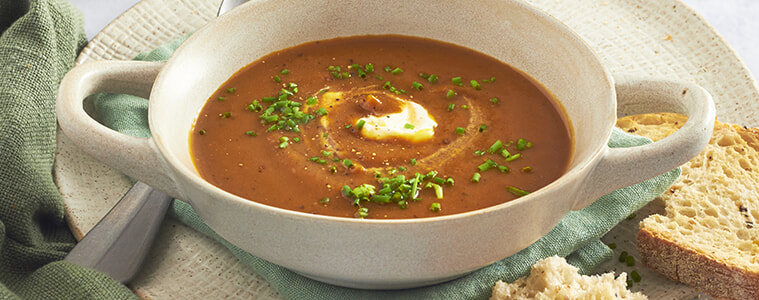 Honey roasted pumpkin soup in a bowl with a side of crusty bread