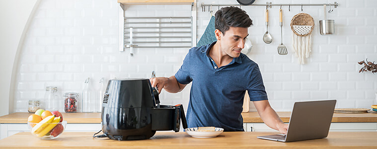 Man cooks breakfast in an air fryer on his kitchen bench