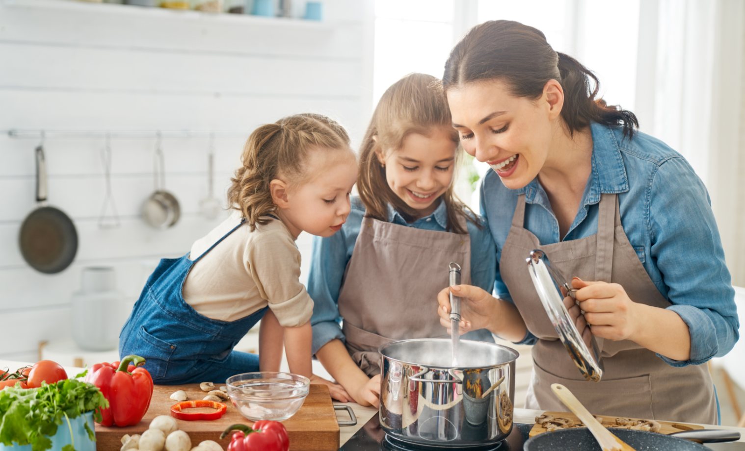 Mum cooking in kitchen with two young daughters