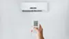 Man pointing remote to air con on the wall.