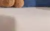 eufy robot vacuum cleaning a living room floor while a woman relaxes on the couch with a laptop