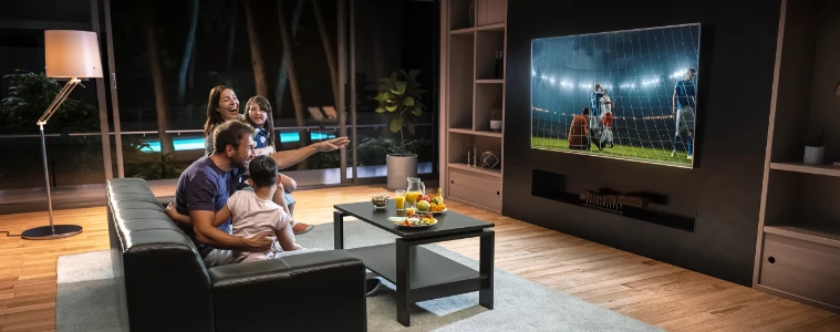 Family watching sports at home on their TV in living room.