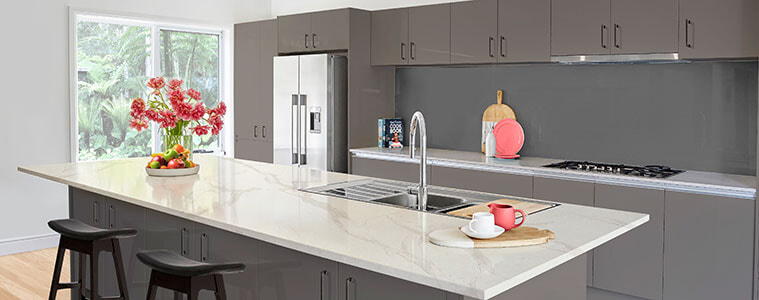 Modern open plan kitchen with grey cabinetry and large kitchen island with silver sink and gooseneck tap
