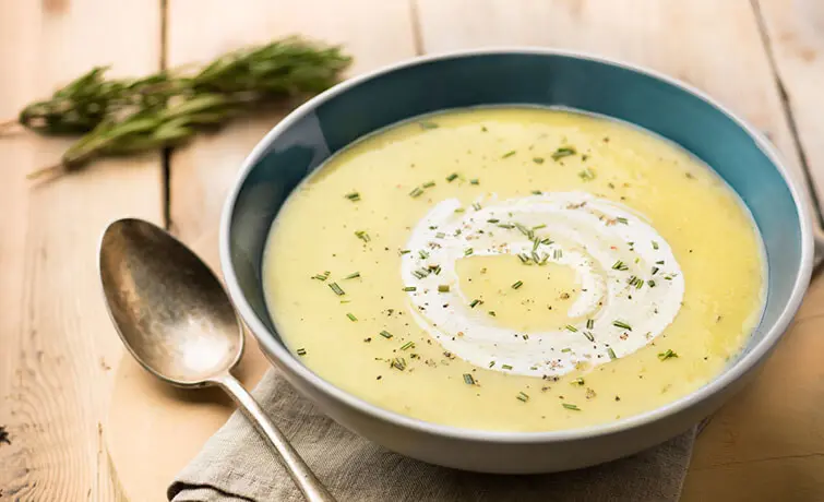 Delicious bowl of hot leek and potato soup on a wooden table