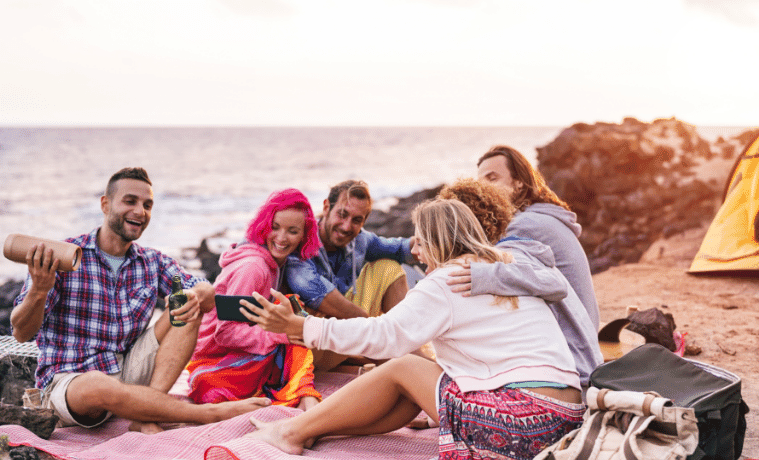Friends sitting on the beach together listening to music 