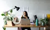 Smiling businesswoman with cat on desk having a coffee in her home office