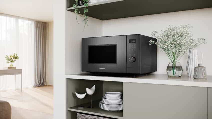 A Westinghouse microwave on a white countertop in a sage green kitchen