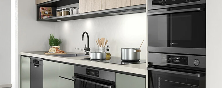 A sage green and light timber kitchen with dark stainless steel appliances