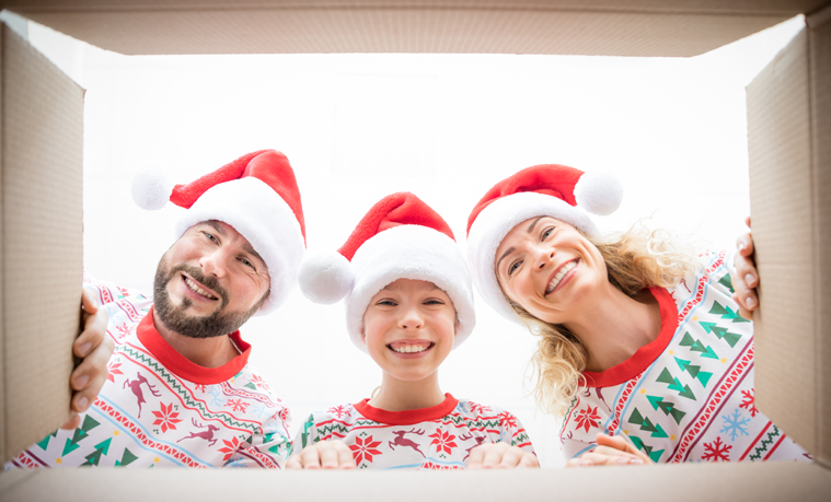Happy family in matching Christmas outfits looking into a big gift box. 
