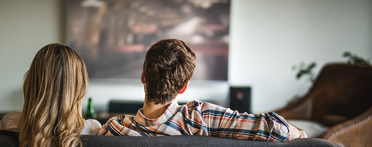 Back view of a couple watching TV on the sofa at home