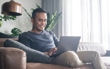 Father using a laptop at home on the couch