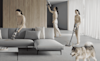 3 versions of the same woman walk around a living room using the different modes of a Dyson stick vacuum