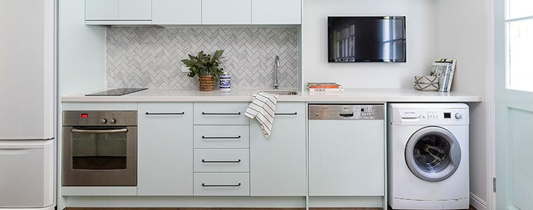 Combined kitchen and laundry in the Hamptons style with stylish white cabinetry and appliances