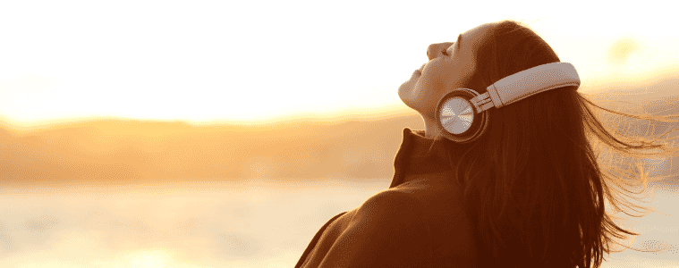 Woman listening to an audiobook through her headphones at the beach