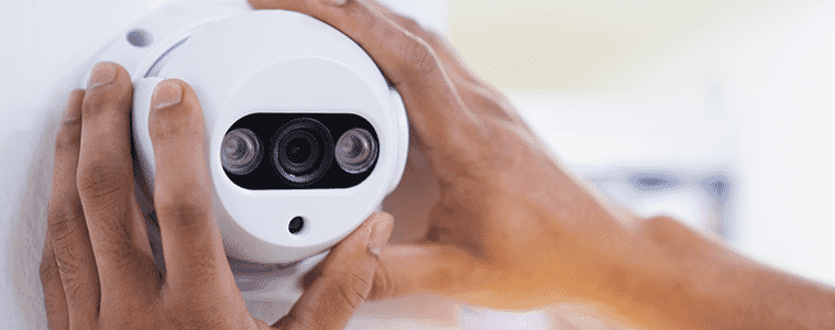 Closeup of a mans hands adjusting the angle of a newly installed security camera